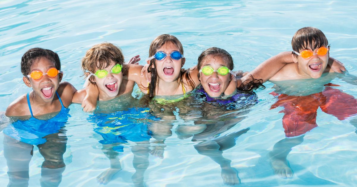 Happy children swimming in a pool wearing colorful goggles